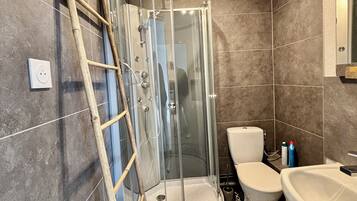 A bathroom with a glass-enclosed shower, a toilet, and a sink.