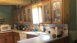 Una cocina con armarios de madera, un microondas y un lavamanos.