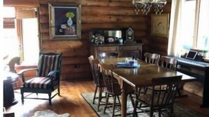 Un comedor rústico de madera con una mesa grande y sillas, una araña y una alfombra.