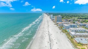 A coastal cityscape with a long beach, high-rise buildings, and a clear blue sky. - Experience Coastal Luxury: 2-Bedroom Oceanfront Condo in Myrtle Beach! (Myrtle Beach)