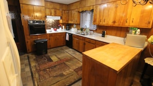 A kitchen with wooden cabinets, a stove, a sink, and a refrigerator. - Mom's House (Augusta)