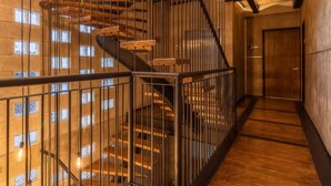 A multi-level interior with a spiral staircase, metal railings, and a wooden floor. - ZIELO Rentals Londres (Mexico City)