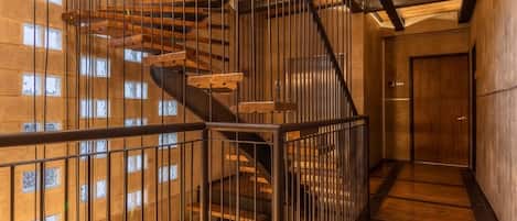 A multi-level interior with a spiral staircase, metal railings, and a wooden floor.