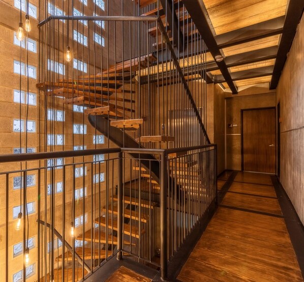 A multi-level interior with a spiral staircase, metal railings, and a wooden floor. - ZIELO Rentals Londres (Mexico City)