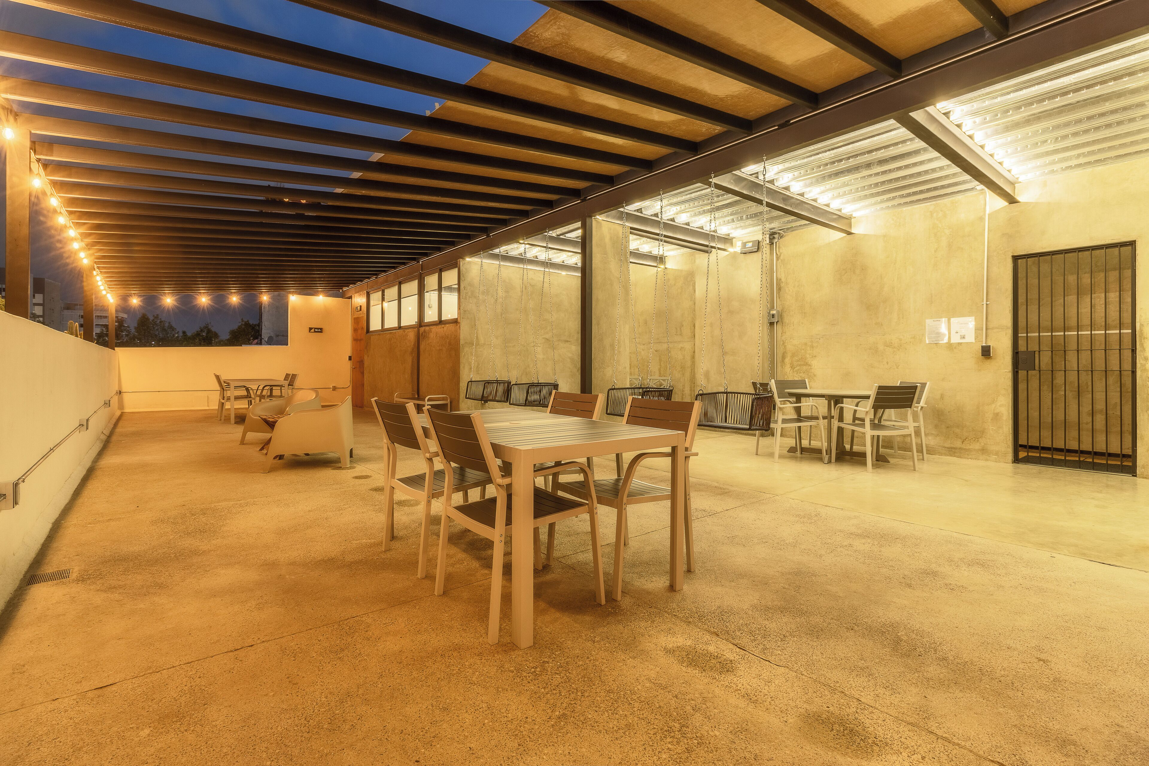 An outdoor patio area with tables and chairs, a covered seating area, and a view of the cityscape.