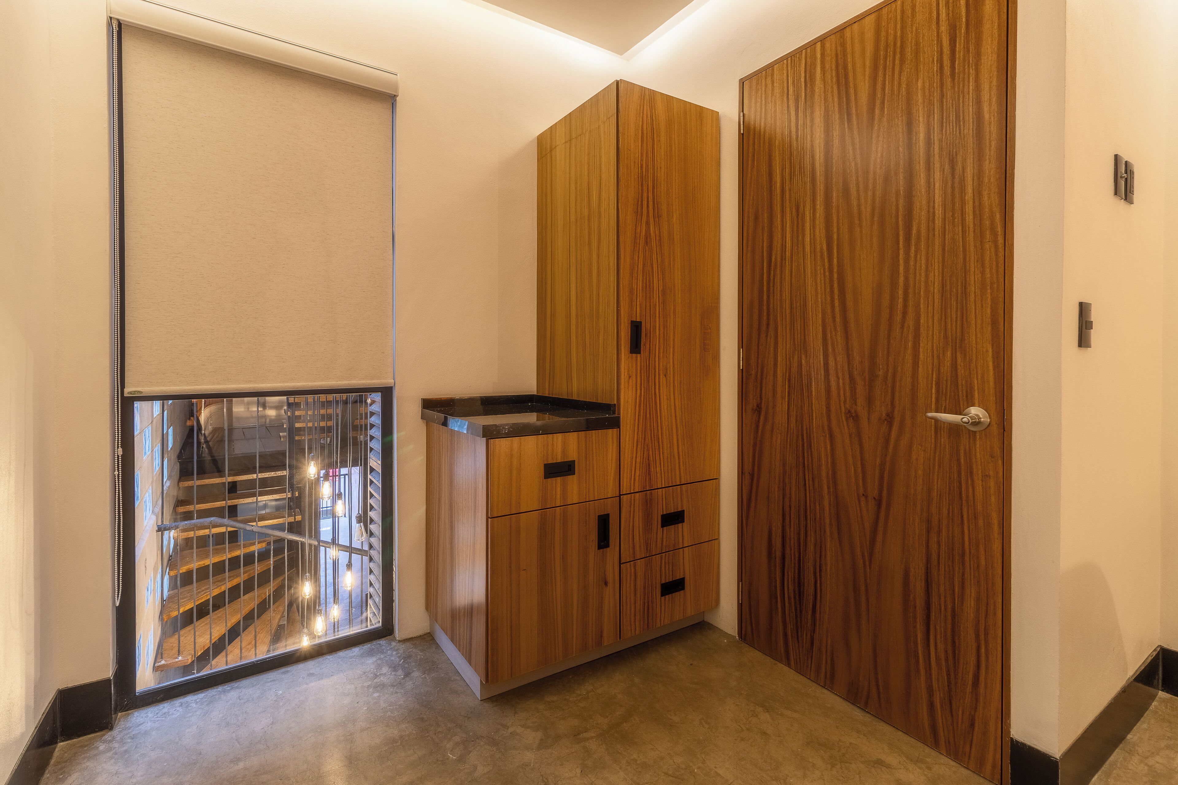 A room with a wooden wardrobe, a small cabinet, and a sliding door.