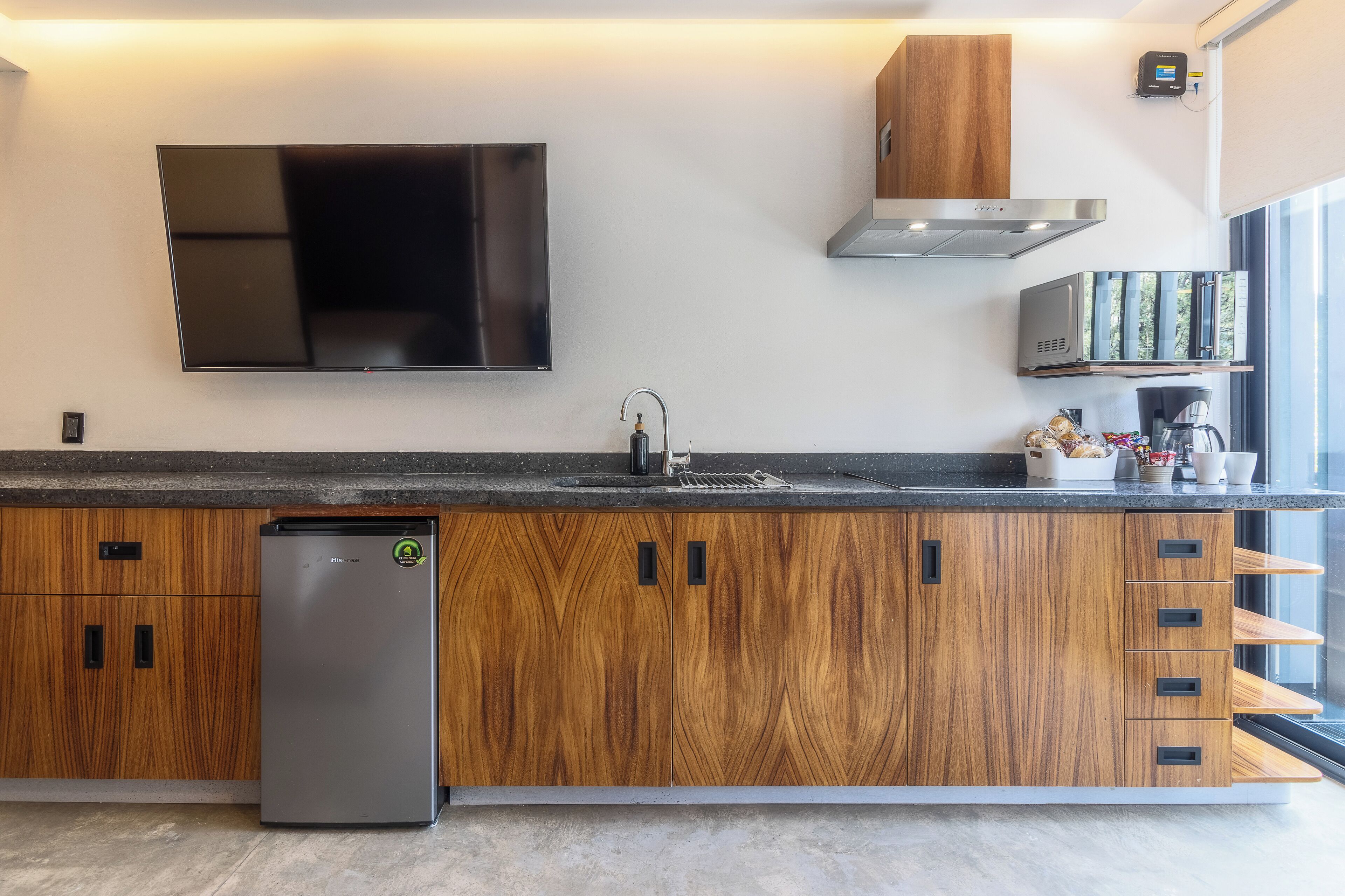 A modern kitchen with a built-in refrigerator, a flat-screen TV, and a microwave.