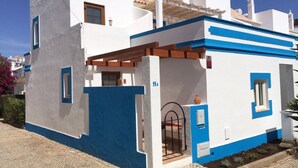 Ein weißes Gebäude mit blauen Akzenten, ein Ziegeldach und eine kleine Veranda.