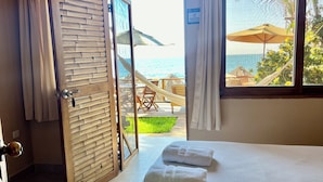 Una habitación de hotel con una cama, vistas al océano y un balcón con mobiliario exterior.