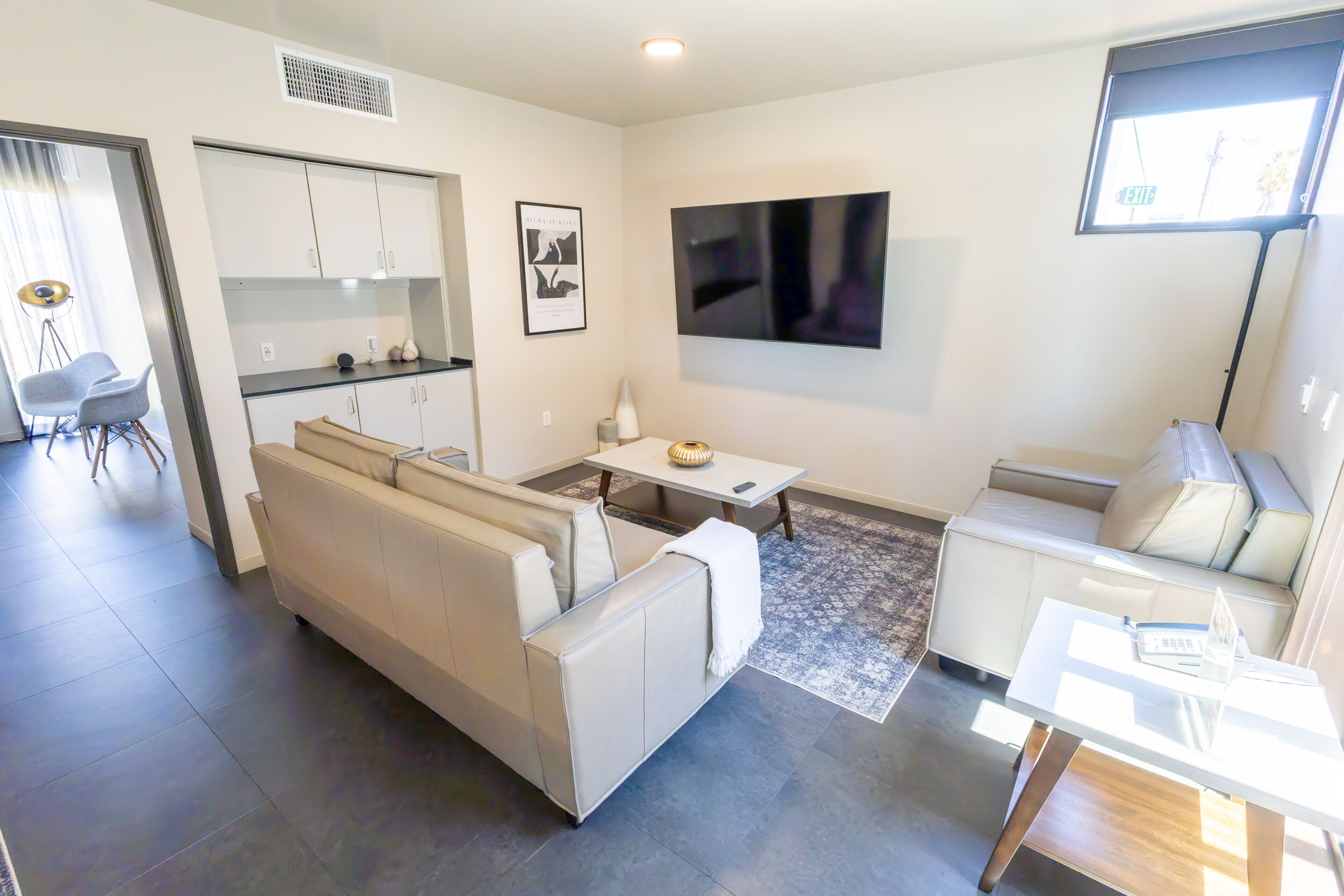 A modern living room with a sofa, a dining table, and a TV mounted on the wall.