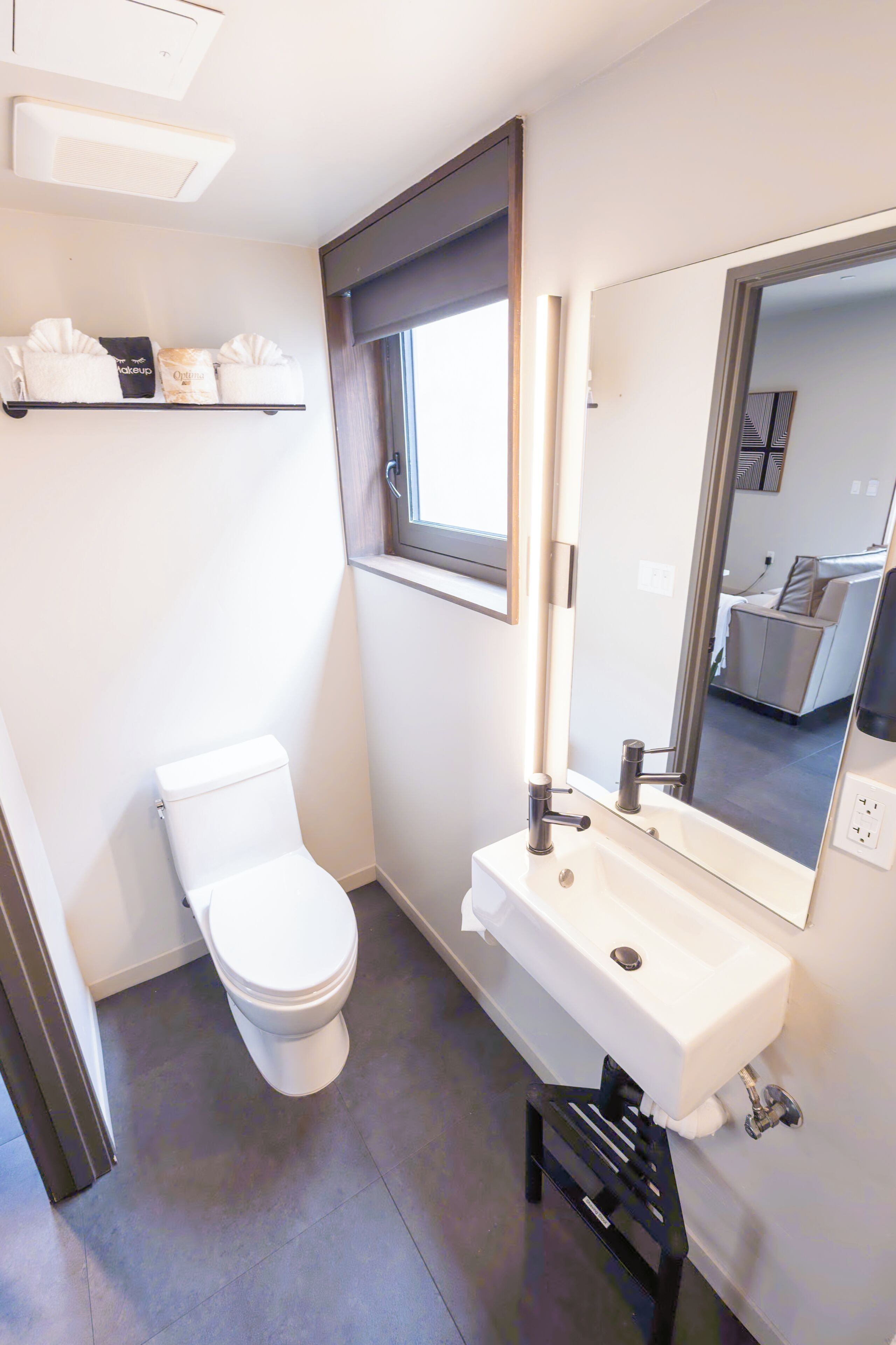 Ein modernes Badezimmer mit Toilette, Waschbecken und Spiegel.