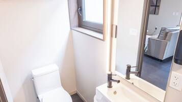 Ein modernes Badezimmer mit Toilette, Waschbecken und Spiegel.