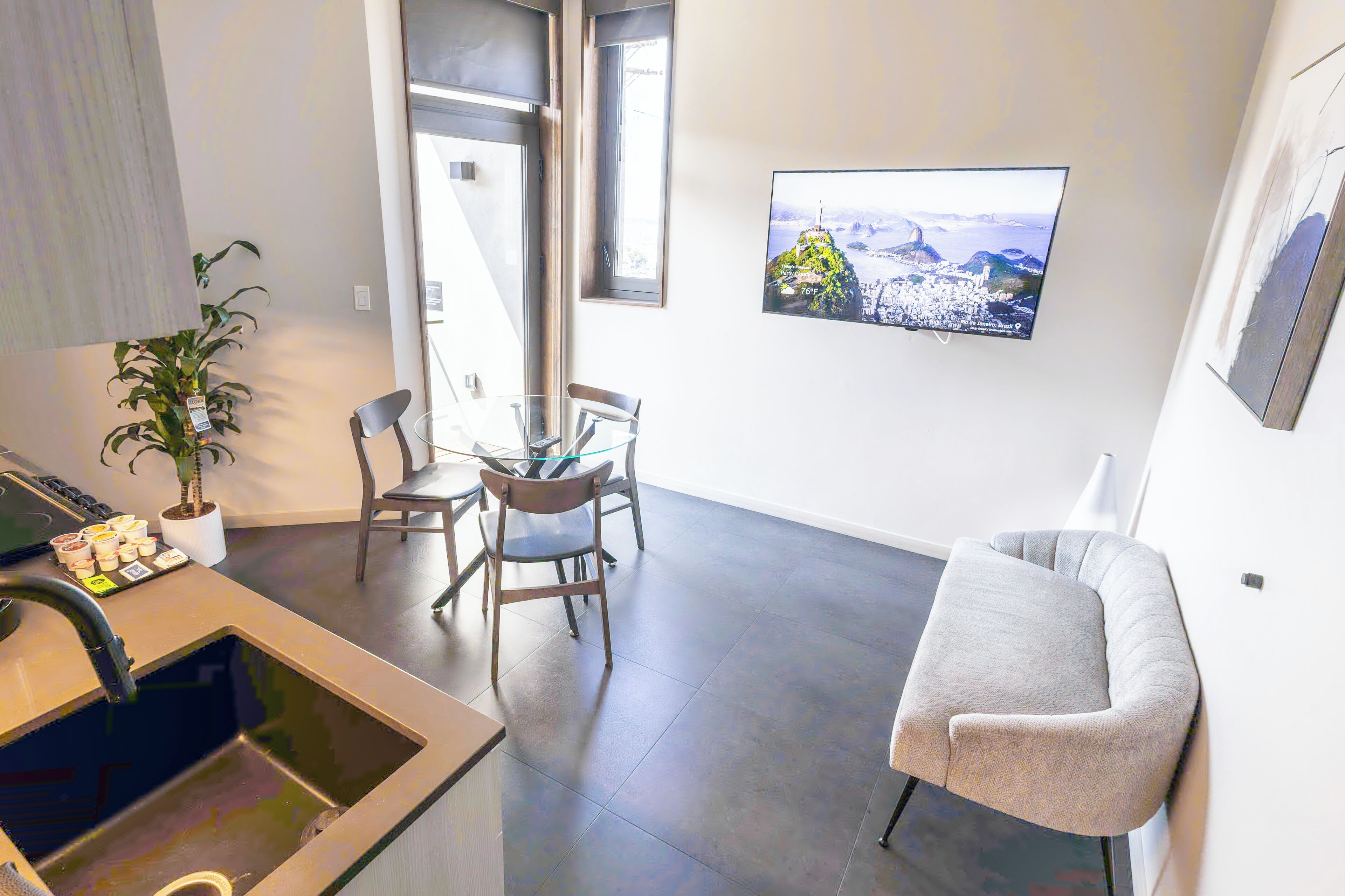 Ein stilvoller Wohnraum mit Essbereich, einer Couch, einem an der Wand befestigten Fernseher und einer Topfpflanze.