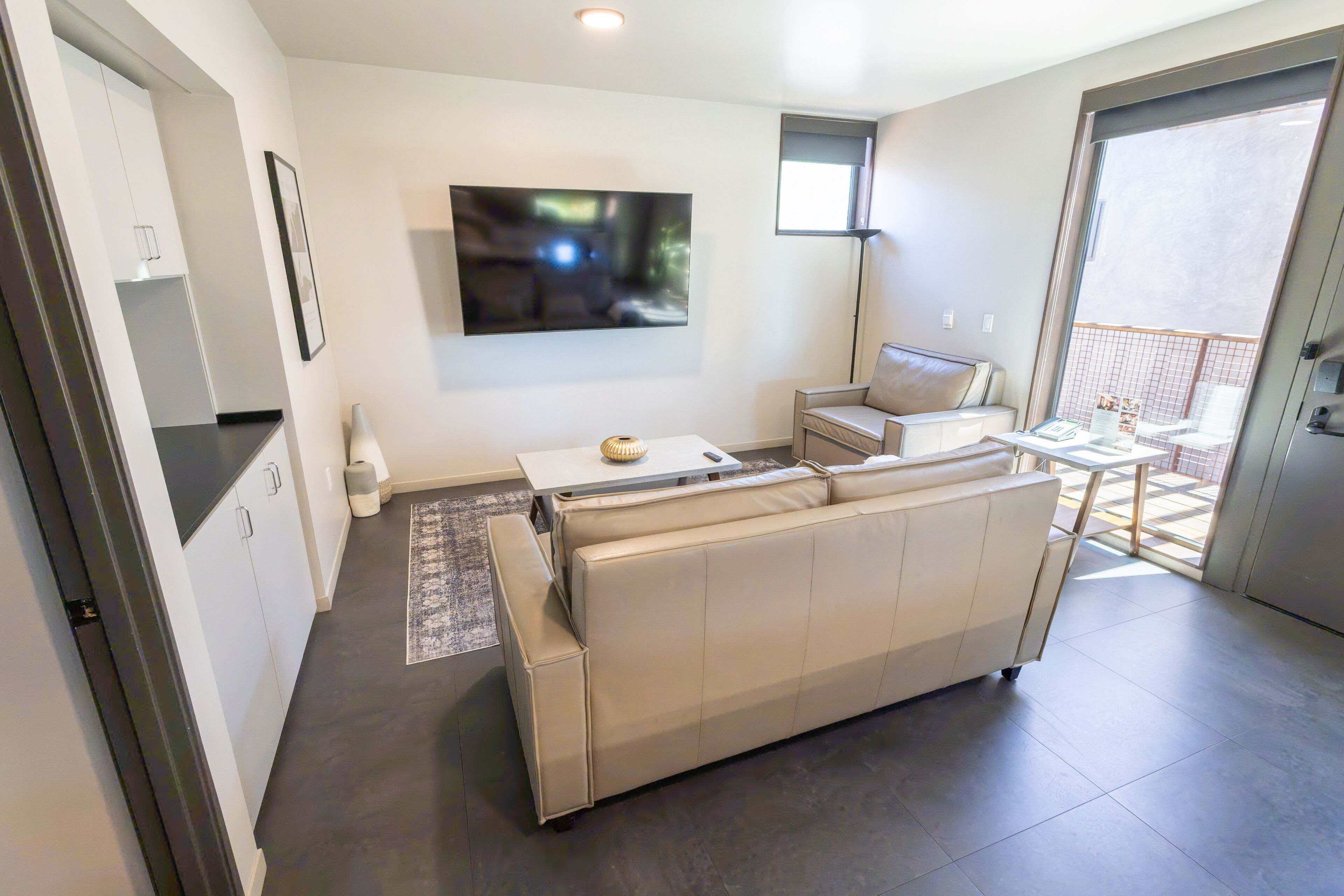 Una sala de estar moderna con un sofá, un televisor de pantalla plana y un comedor con mesa y sillas.