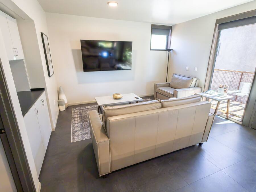 Una sala de estar moderna con un sofá, un televisor de pantalla plana y un comedor con mesa y sillas.