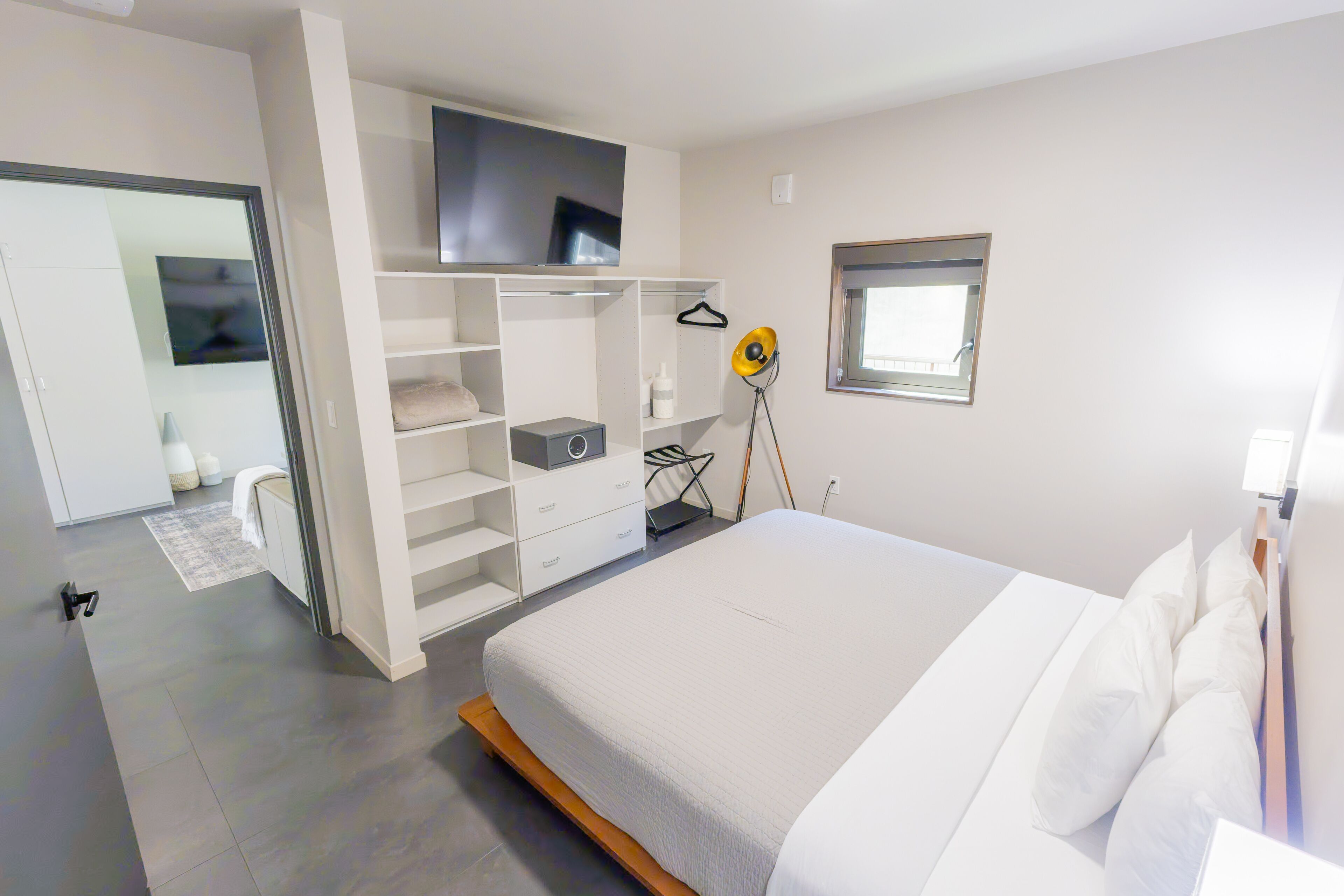 Une chambre moderne avec un lit, un téléviseur fixé au mur, une armoire et une table de chevet.