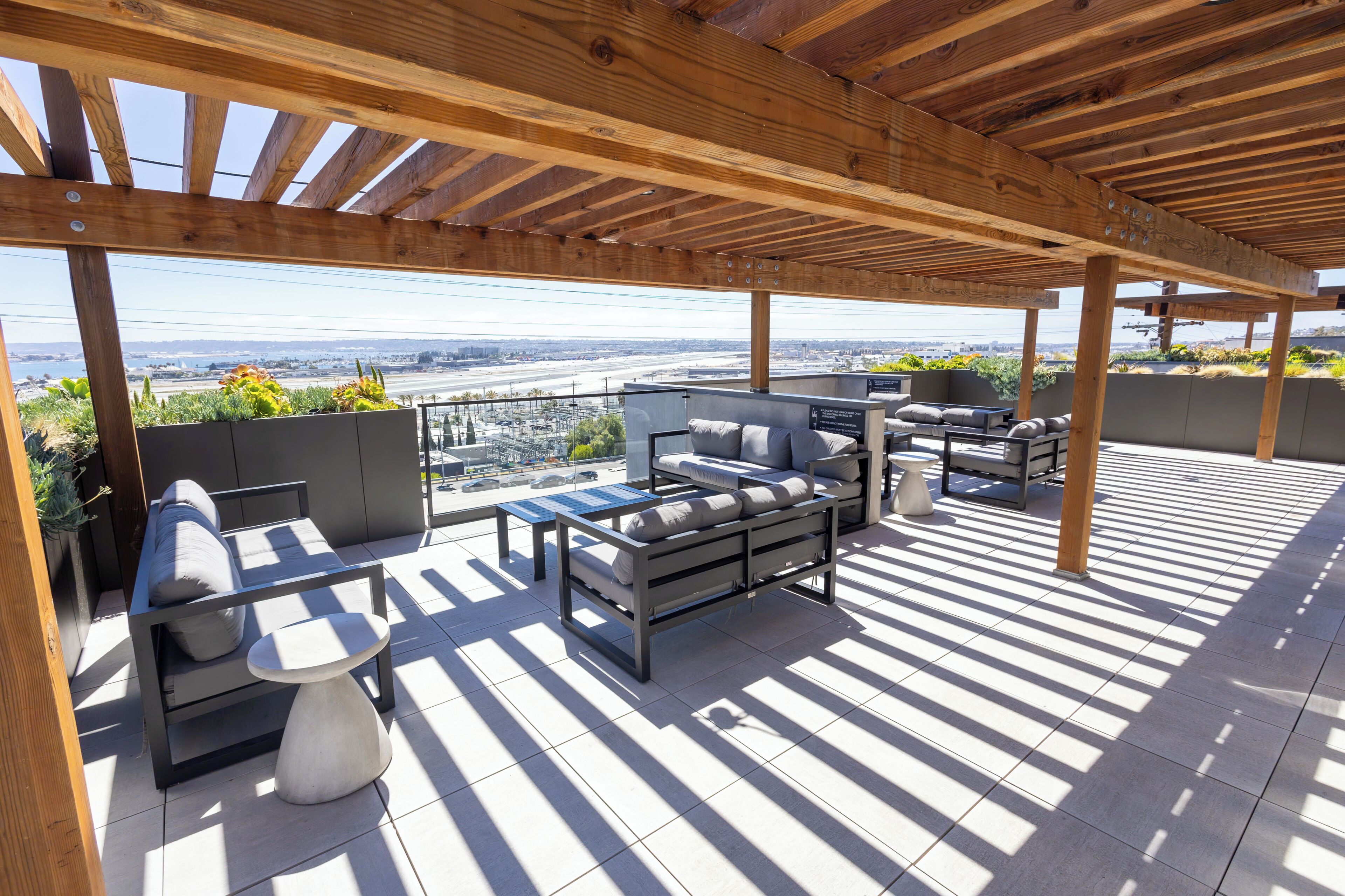 Un patio al aire libre con pérgola, zona de estar y vista de la ciudad.