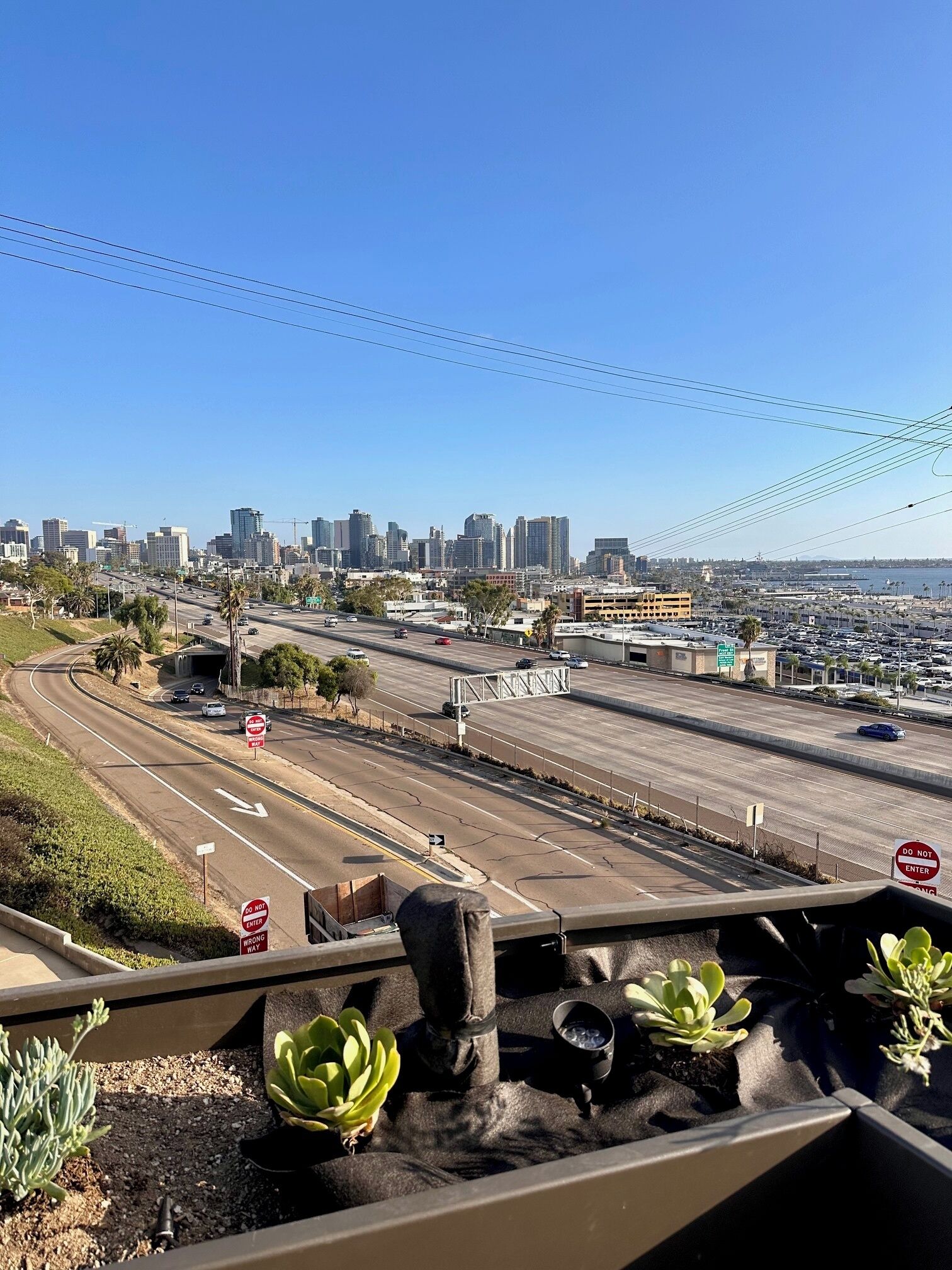 A cityscape with a clear sky, a highway, and a parking lot.