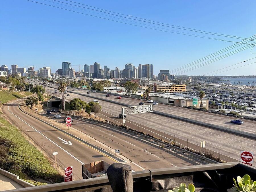 A cityscape with a clear sky, a highway, and a parking lot.