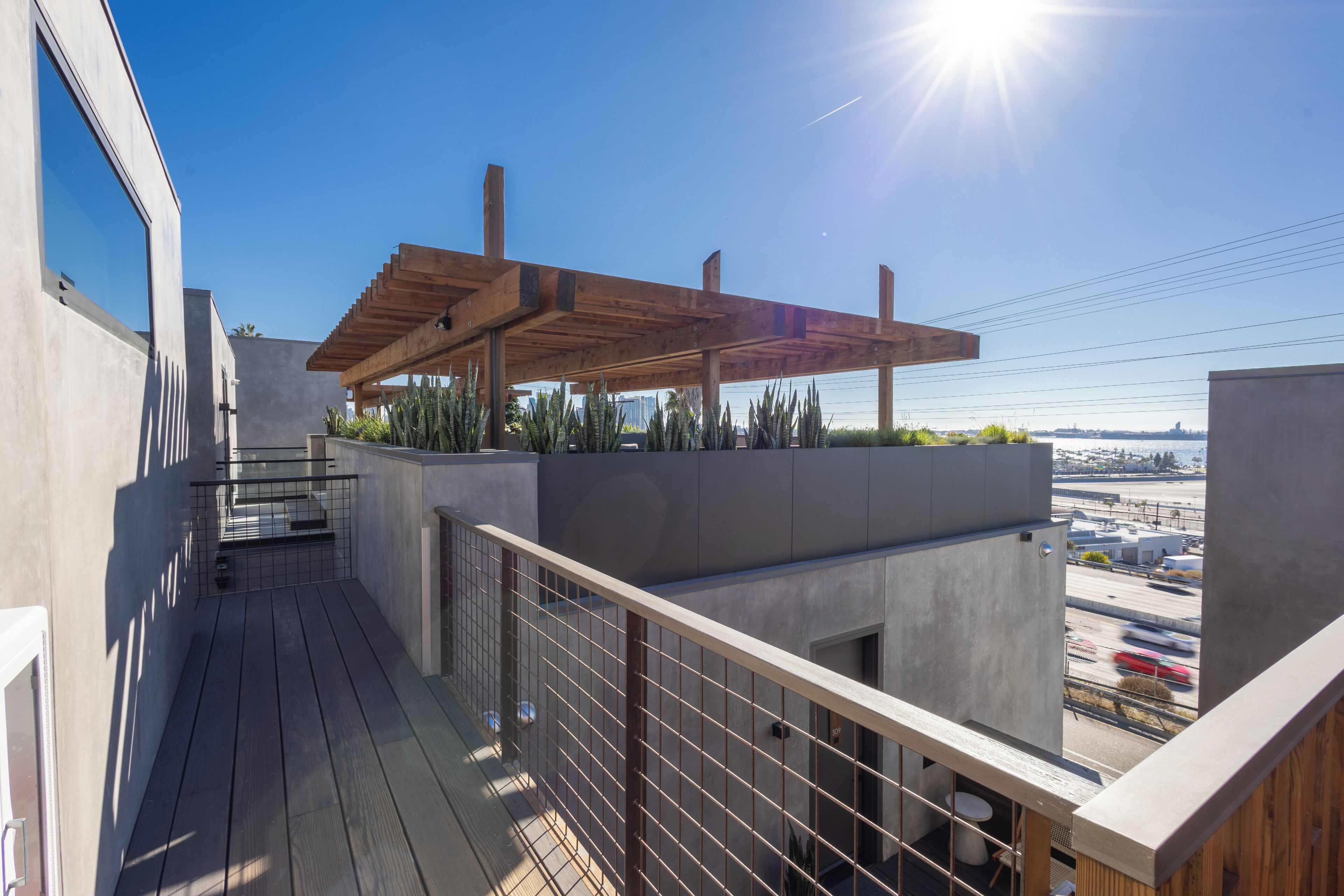 Un balcón con una pérgola de madera, vistas de la ciudad y cielo despejado.