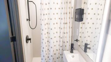 Ein modernes Badezimmer mit Dusche, Waschbecken und Spiegel.