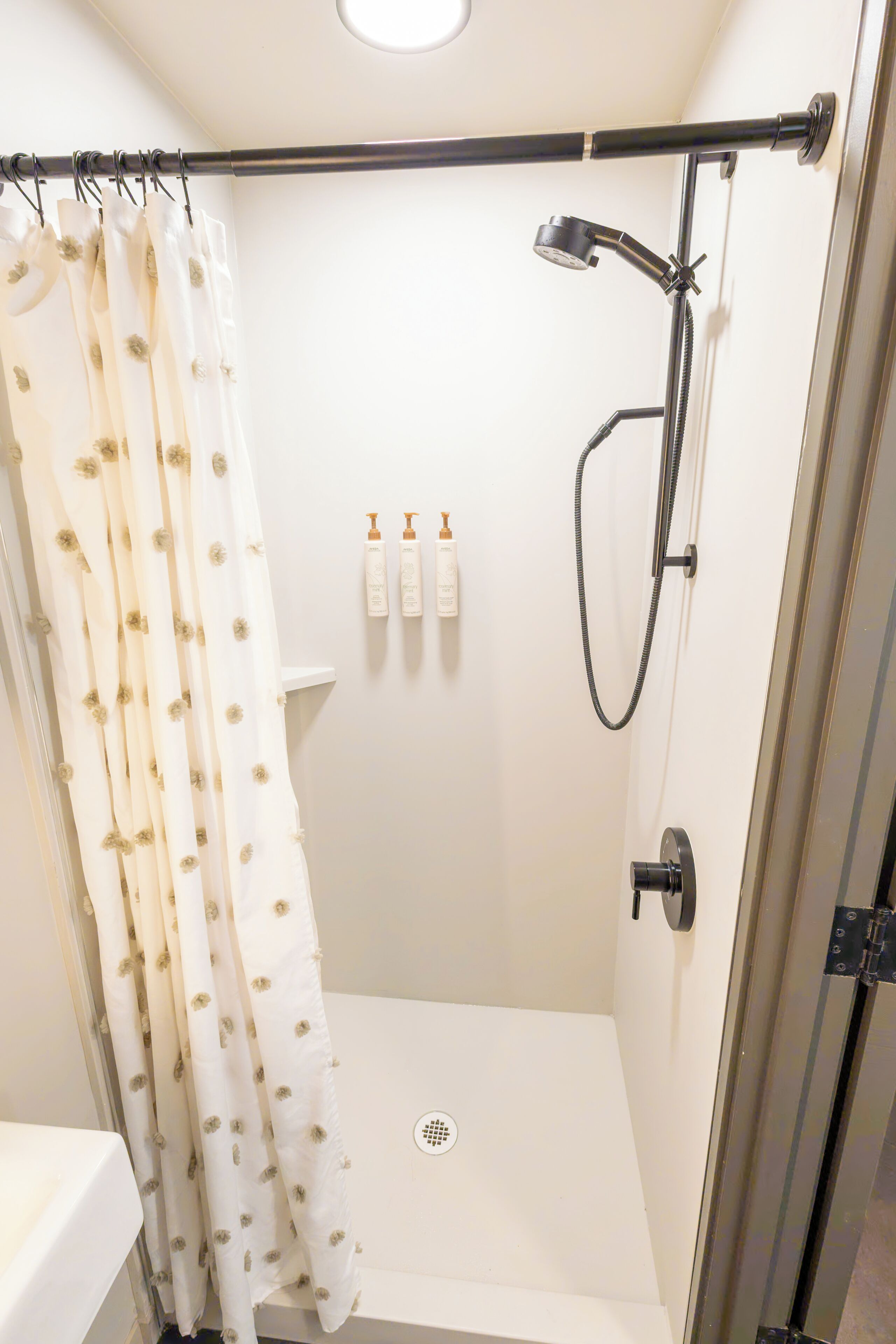 Un espace douche doté d’une porte en verre, d’un pommeau de douche et d’un flexible de douche.