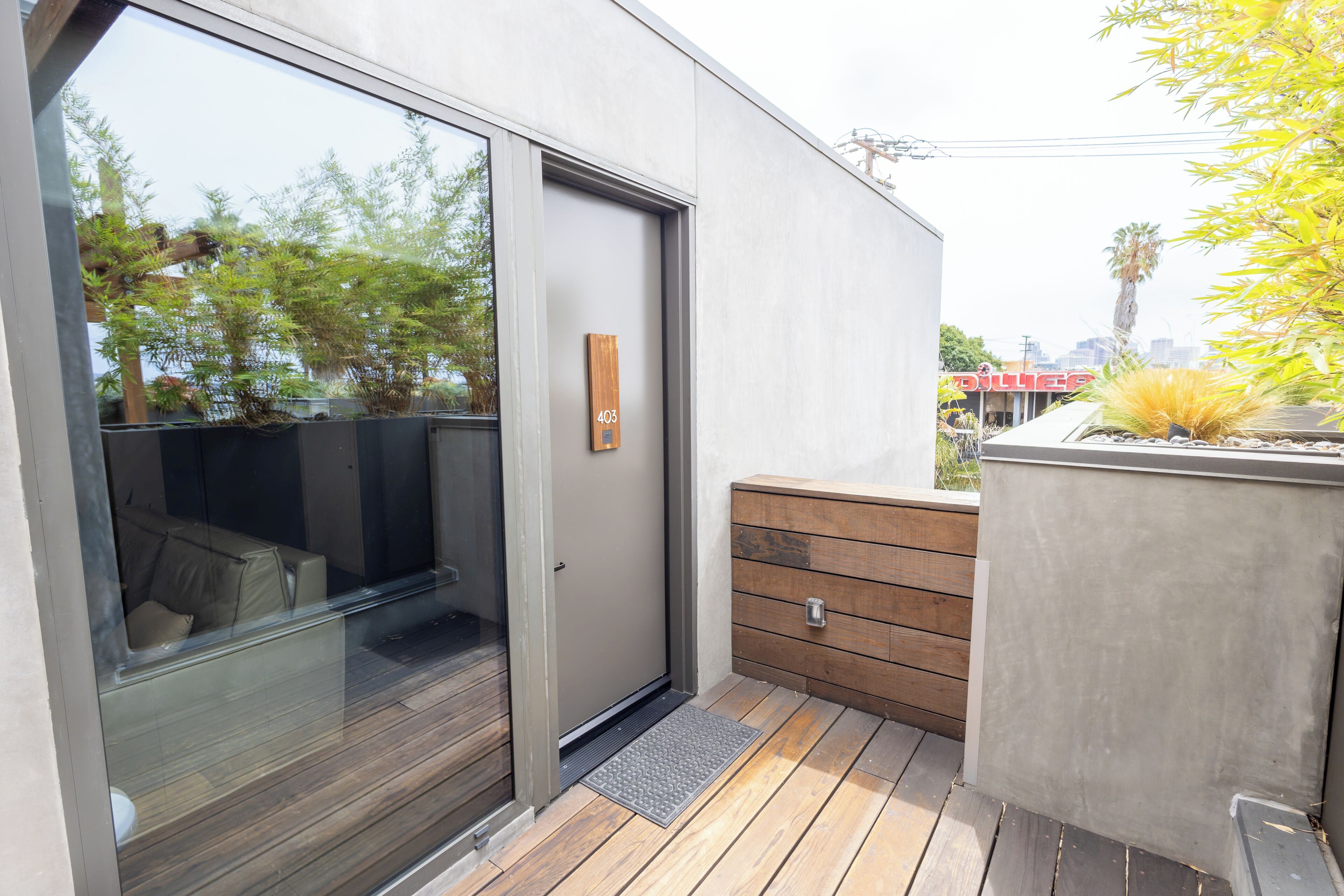 Un bâtiment moderne doté d’une porte coulissante en verre, d’un banc en bois et d’un cadre de porte en métal.
