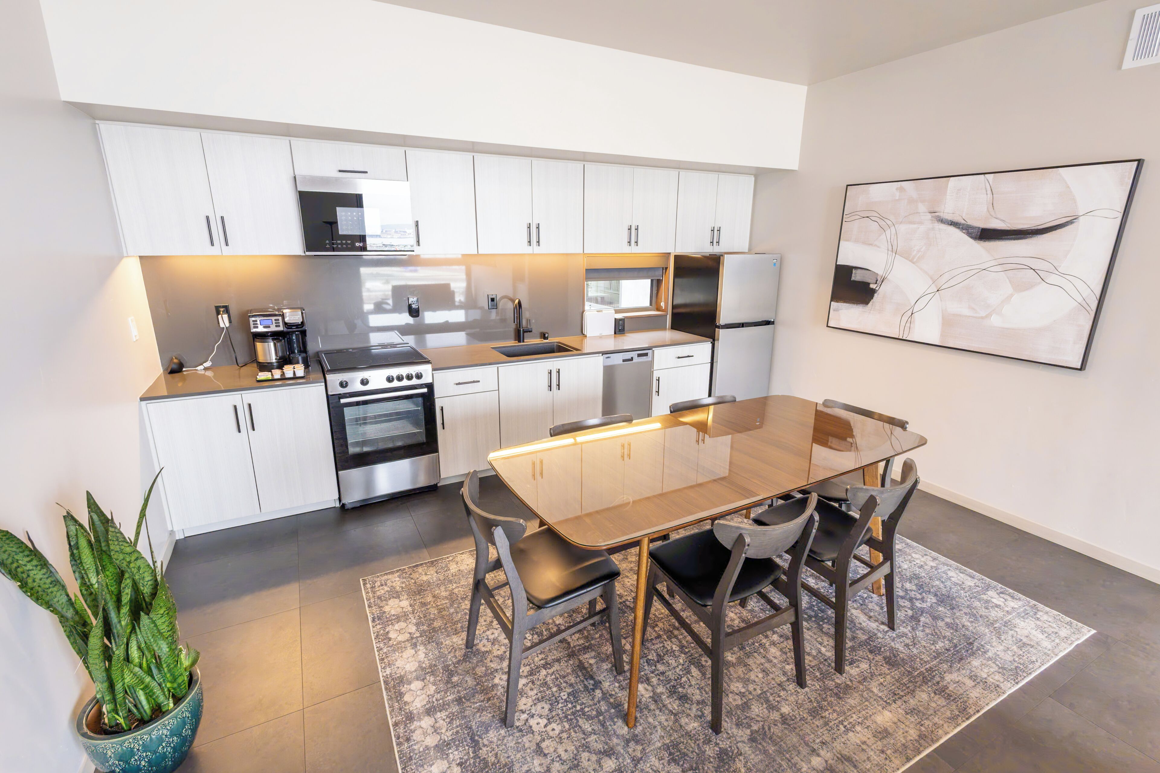 A modern kitchen with white cabinets, stainless steel appliances, and a dining area with a glass table and chairs.