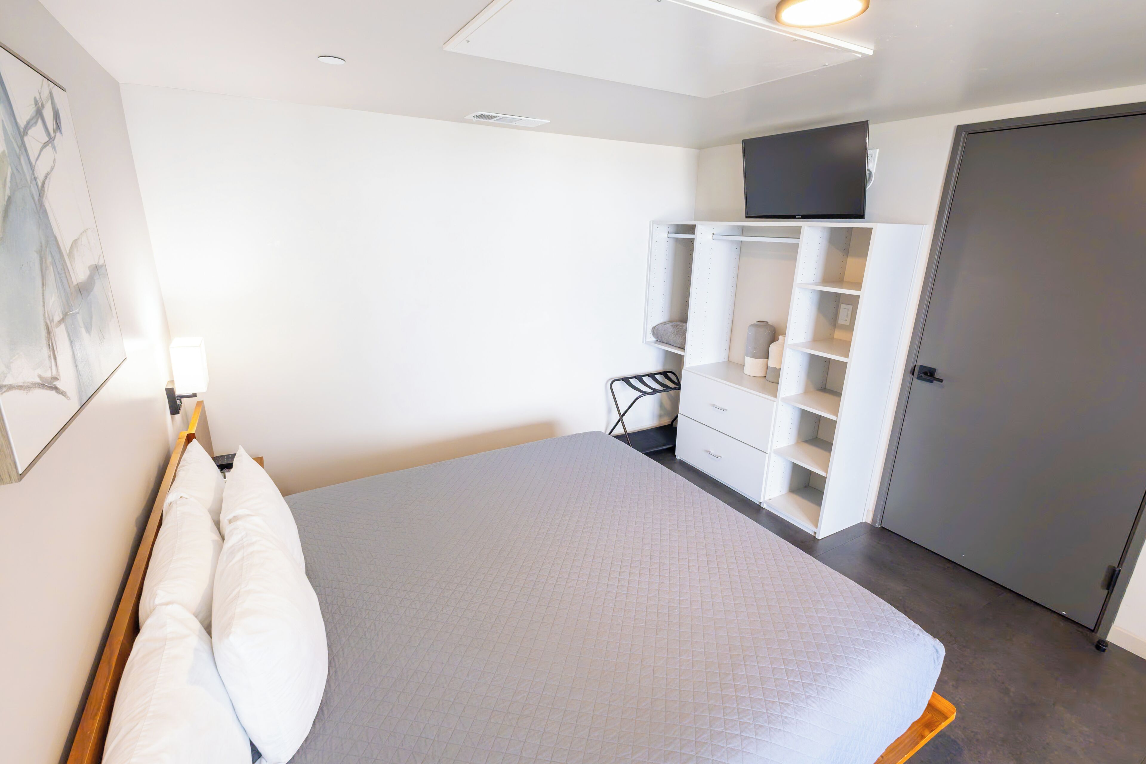 Un dormitorio moderno con cama, armario y puerta.