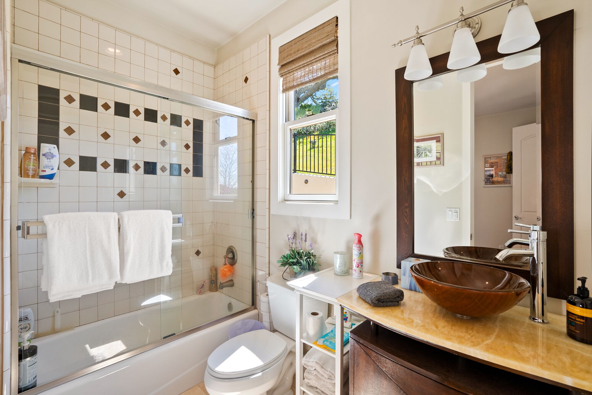 Un baño moderno con ducha de vidrio, un espejo grande y un lavabo de madera.