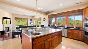 A spacious kitchen with a large island, wooden cabinets, and a view of the outdoors.