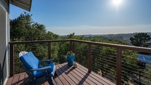 Una terrassa de fusta amb dues cadires blaves i una planta en test, amb vista a un paisatge idíl·lic.