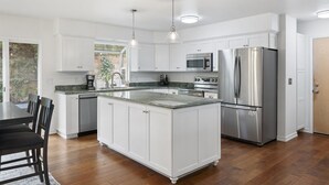 Una cocina moderna con armarios blancos, electrodomésticos de acero inoxidable y una isla central.