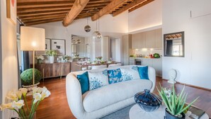 A modern living room with a sofa, a dining area, and a kitchen. - De Nobili Penthouse in Lucca (Lucca)