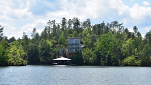 Una propietat a la vora d'un llac amb un edifici de diversos pisos, envoltada per un bosc dens.