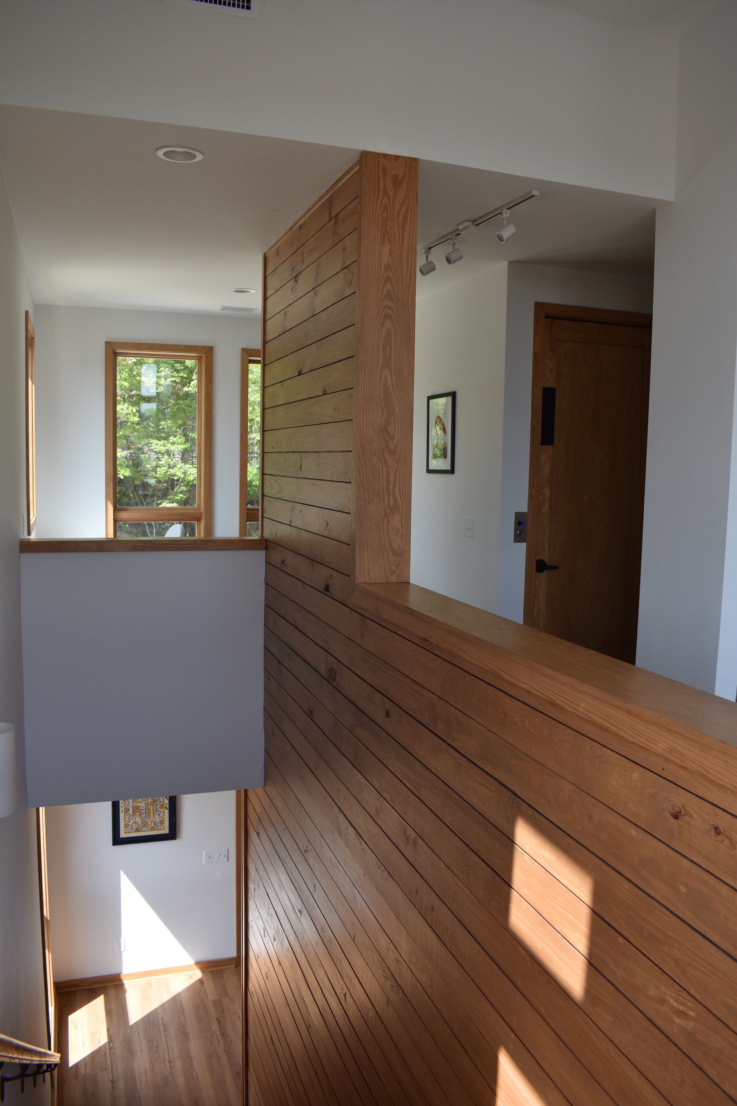 Un intérieur moderne avec un lambris en bois, un escalier et une porte donnant sur une autre pièce.