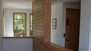 Un interior modern amb panells de fusta, una escala i una porta que condueix a una altra habitació.