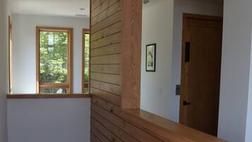 Un intérieur moderne avec un lambris en bois, un escalier et une porte donnant sur une autre pièce.