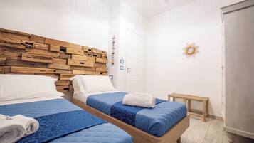 Ein Hotelzimmer mit zwei Betten, einem Holzkopfende, weißen Wänden und einem kleinen Fenster.