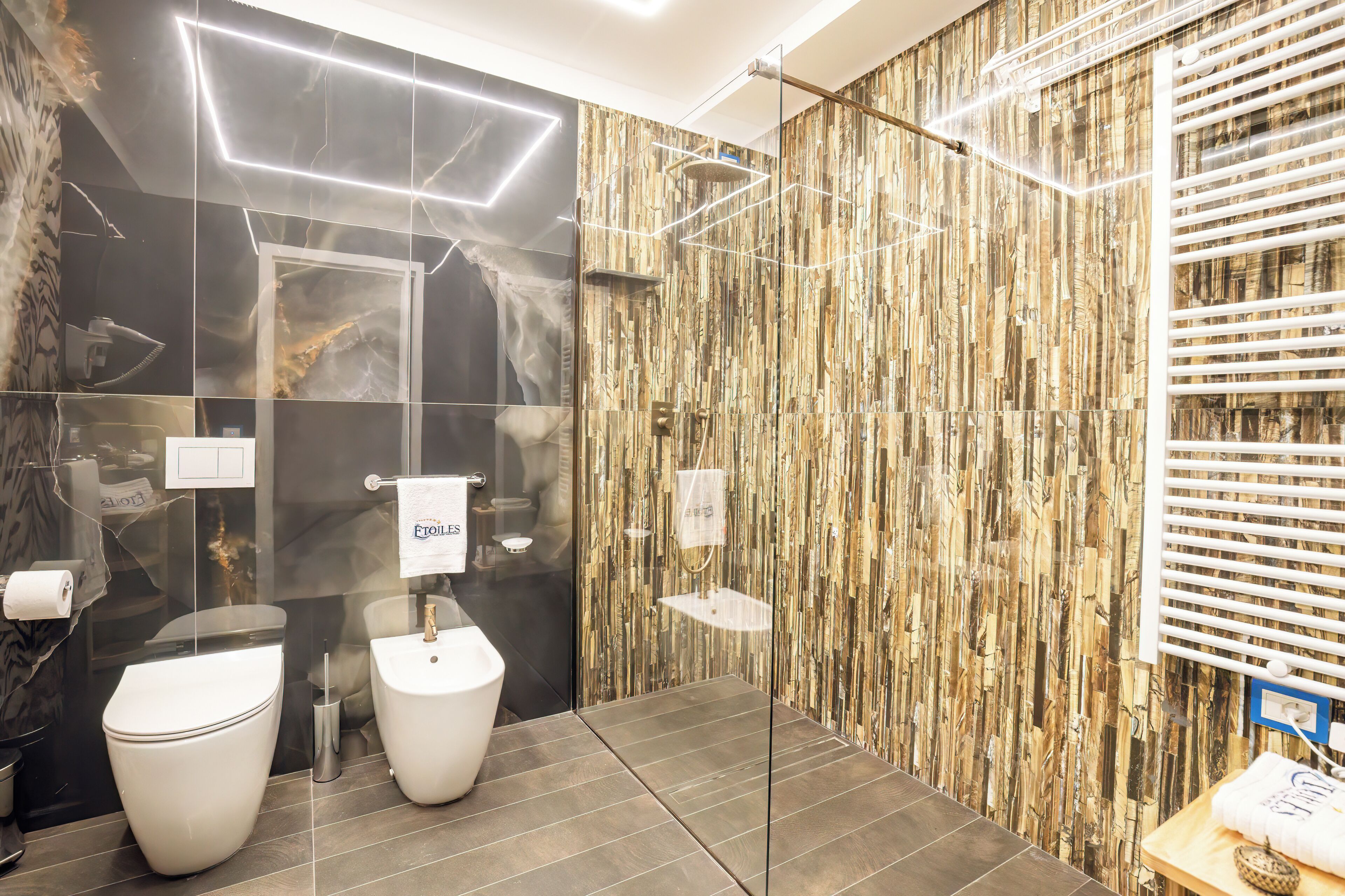 A modern bathroom with two toilets, a shower, and a vanity with a mirror.