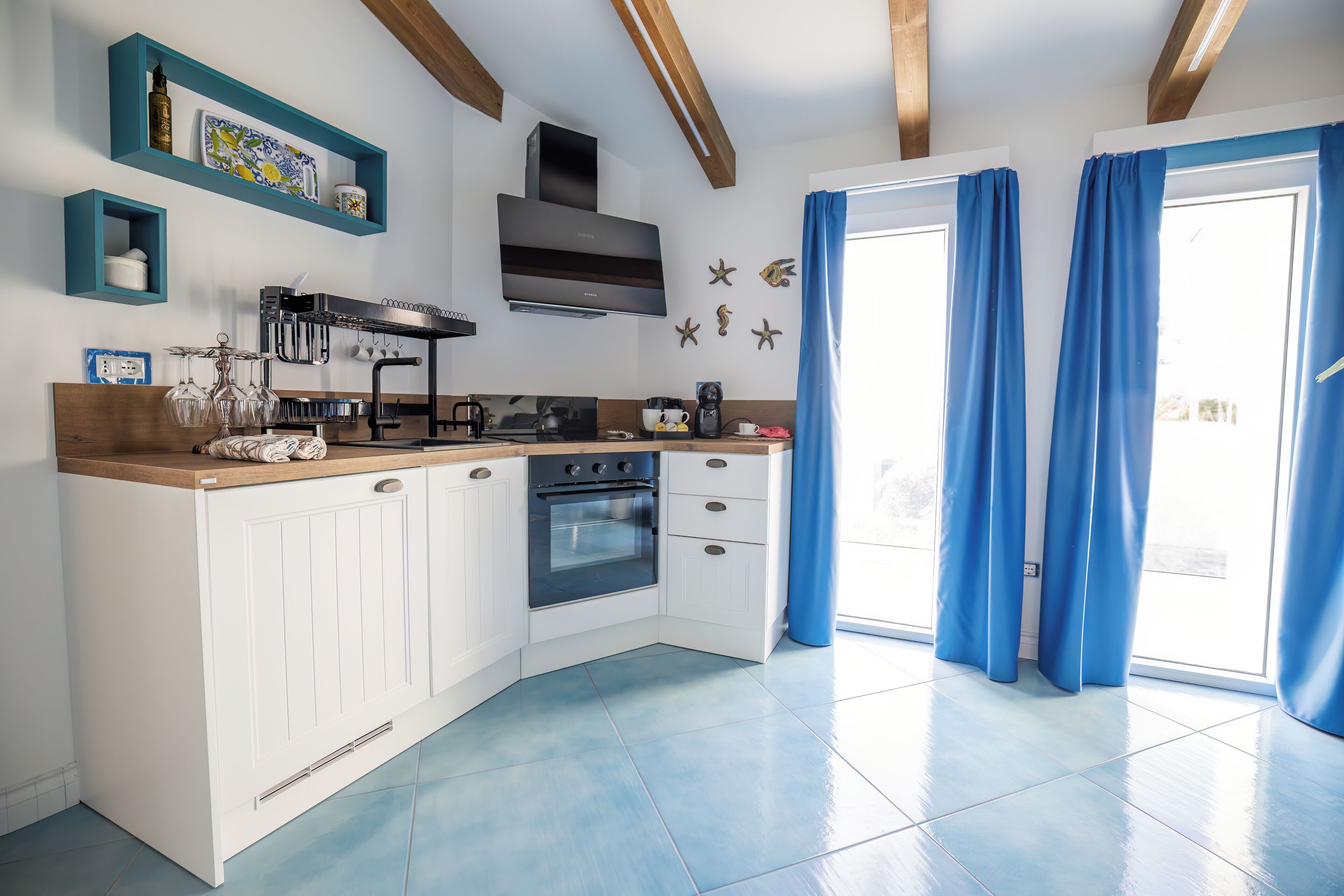 A modern kitchen with white cabinets, a built-in oven, and a blue-tiled floor.