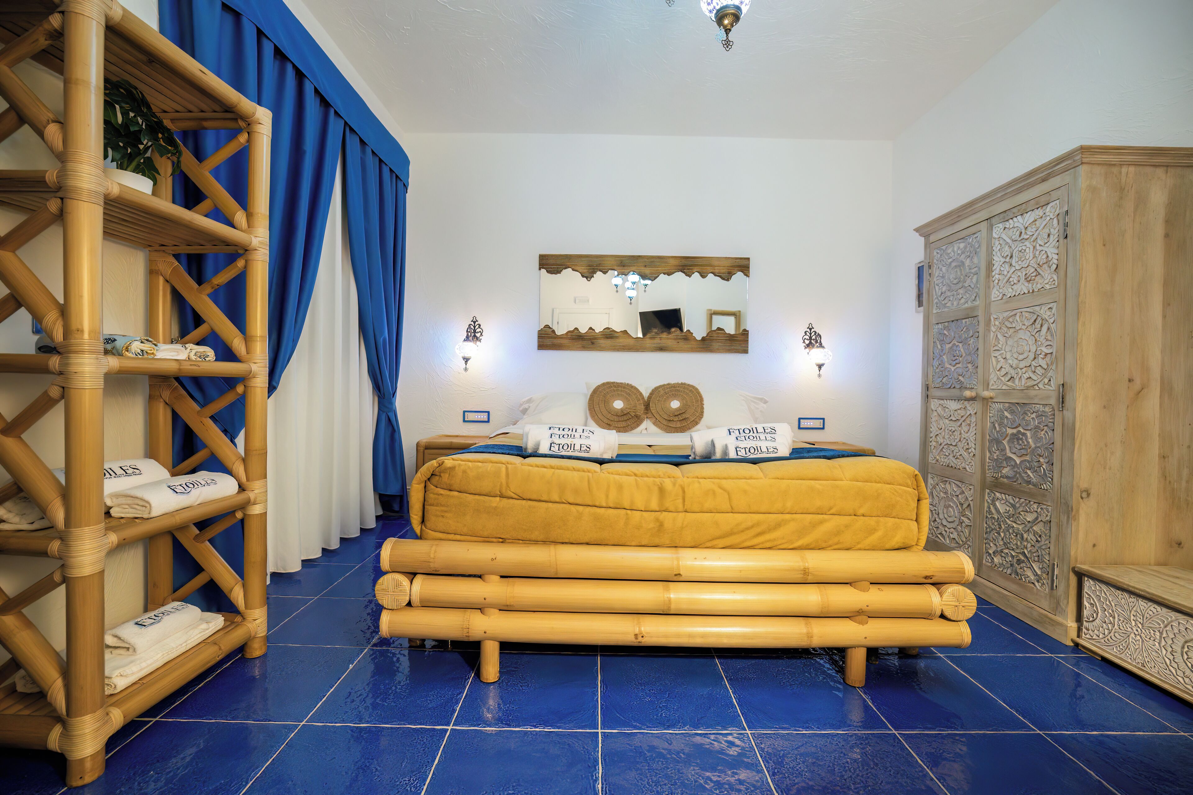 Una stanza con un letto, un armadio in legno, uno scaffale con asciugamani e uno specchio a parete.