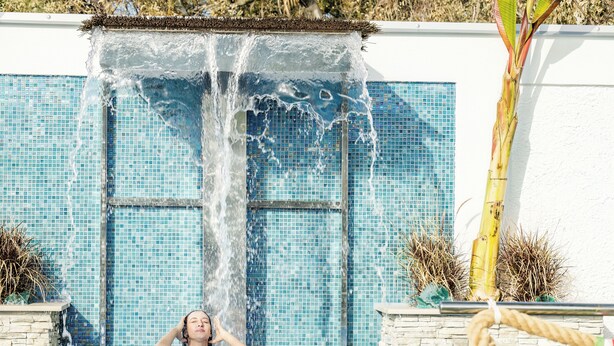Una piscina con una fuente de agua y un muro de azulejos.