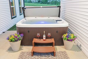 A hot tub with a wooden bench and two potted plants, each with a bottle and glass of red wine. - LUX Farmhouse on Bourbon Trail! Hot tub, Game Room, Firepit, Private, 5-Acres (Bagdad)