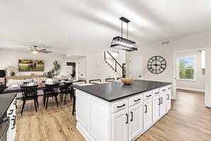 A spacious kitchen with a large island, white cabinetry, and a modern pendant light. - LUX Farmhouse on Bourbon Trail! Hot tub, Game Room, Firepit, Private, 5-Acres (Bagdad)