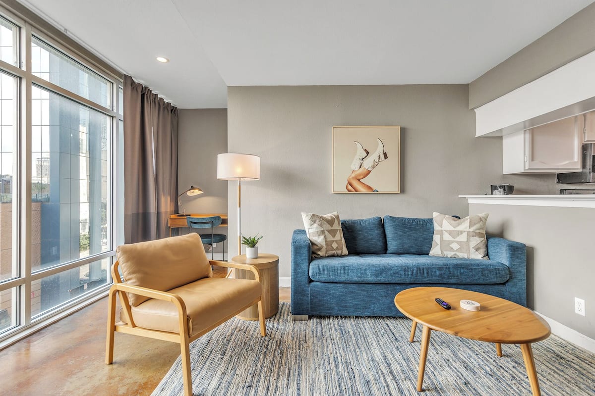 A modern living room with a sofa, armchair, coffee table, and a lamp.