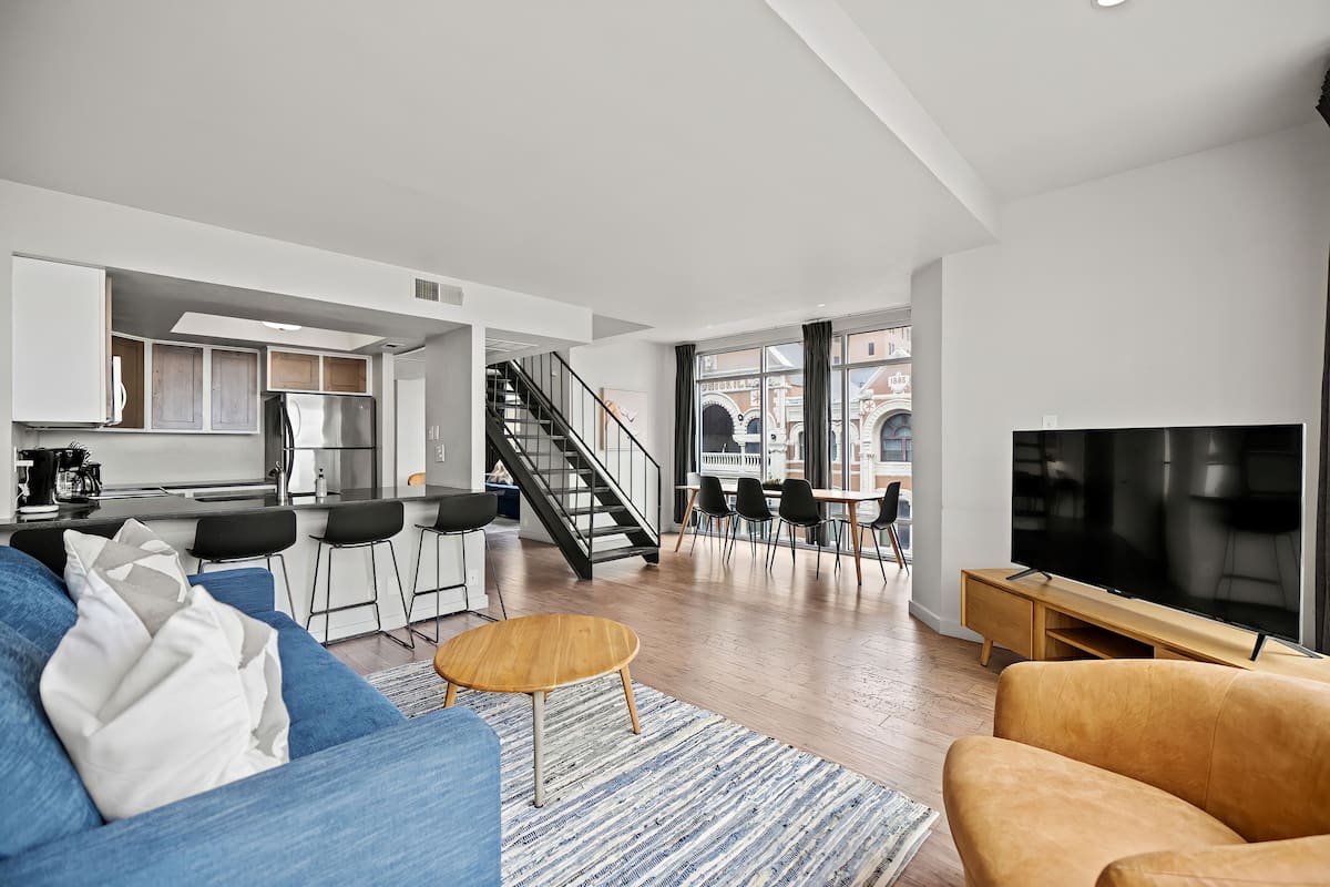 A modern living space with a kitchen, dining area, and a large TV.