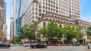 A city street with tall buildings, including a prominent beige building with a clock tower. - Littlefield Lofts, hosted by Placemakr - 6th Street (Austin)