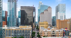 A cityscape with modern and historic buildings, including a prominent glass skyscraper and a traditional brick building with a sign. - Littlefield Lofts, hosted by Placemakr - 6th Street (Austin)