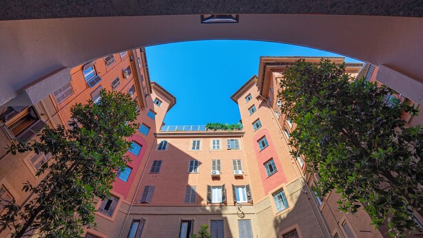 A view through a curved architectural feature, revealing a multi-story building with balconies, windows, and a clear blue sky. - Stilysh apartment in Rome close to cafes, restaurants, bus and metro. (Roma)